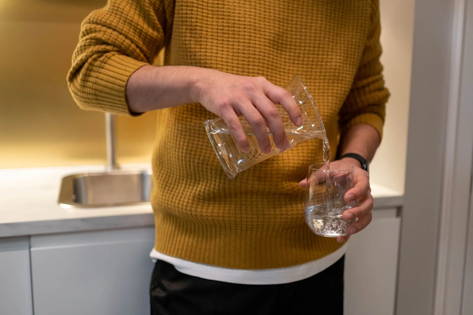 Pouring filtered water into a glass in a modern kitchen