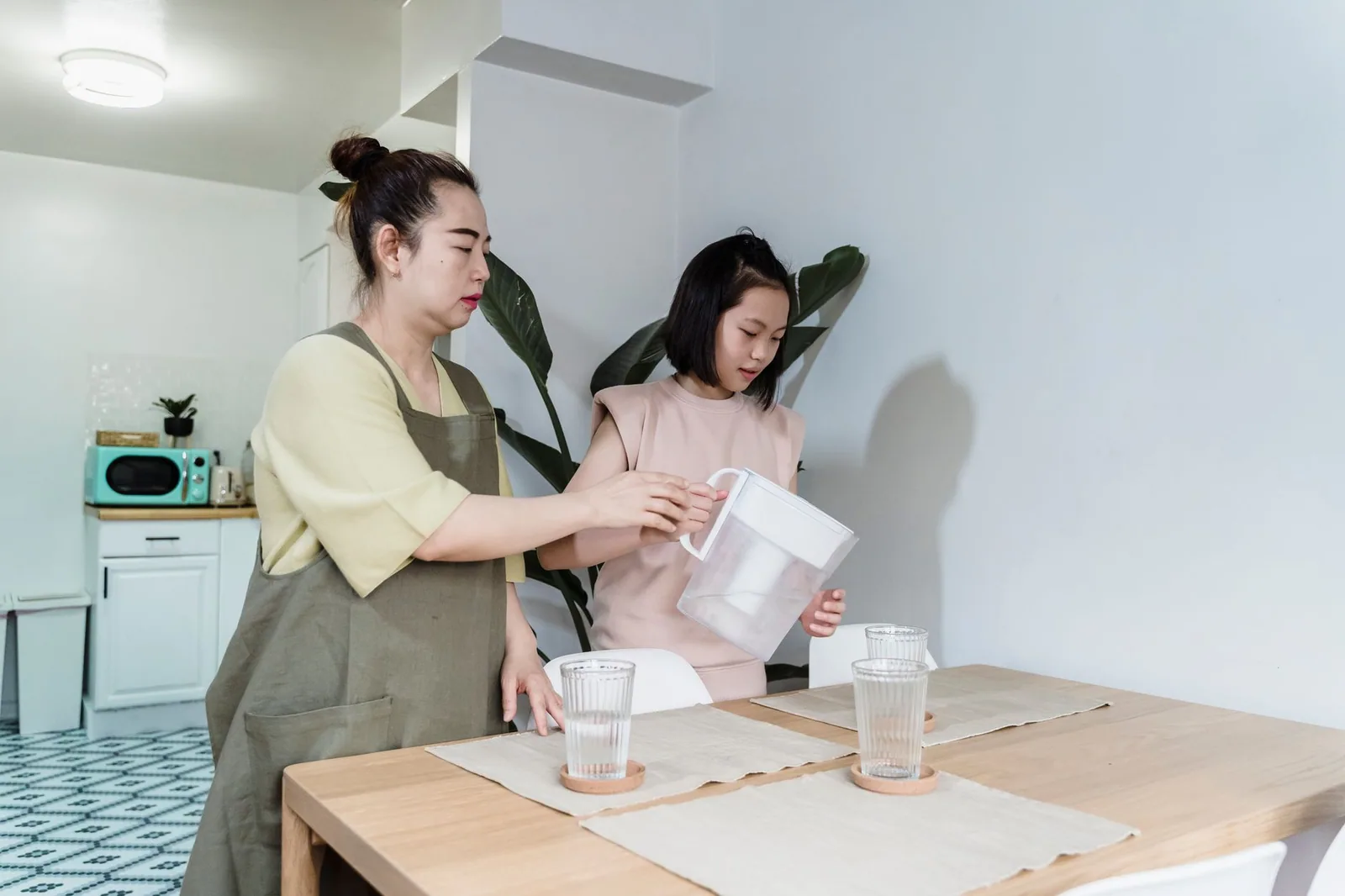 A parent and child filling a filter jug at the kitchen table