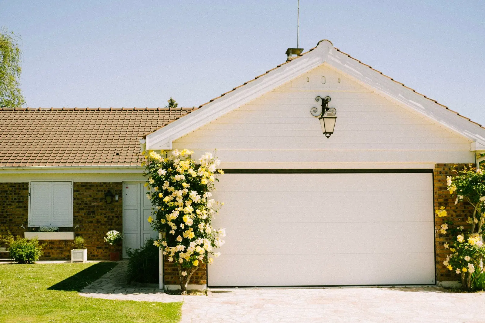 A suburban house with an attached garage and flowering plants
