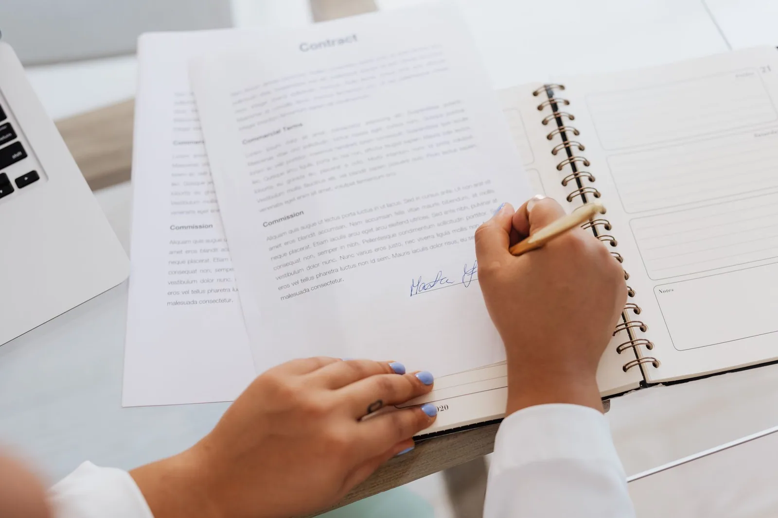 A homeowner signing a printed contract at a desk, pen in hand