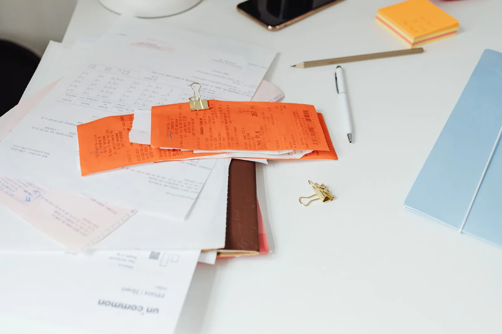 Printed receipts and documents spread across a desk beside office supplies