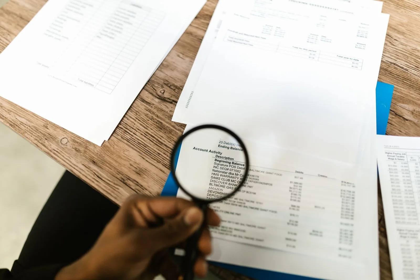 A hand holding a magnifying glass over the printed lines of a document
