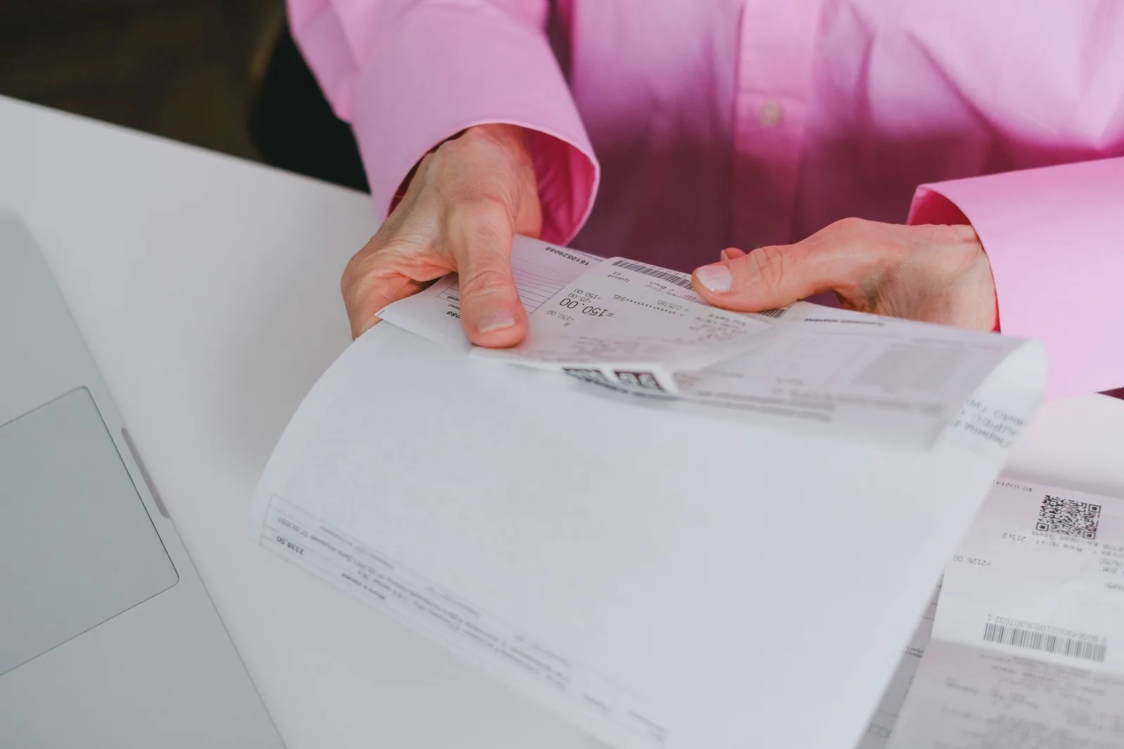 A hand holding a long printed receipt, line items facing the camera