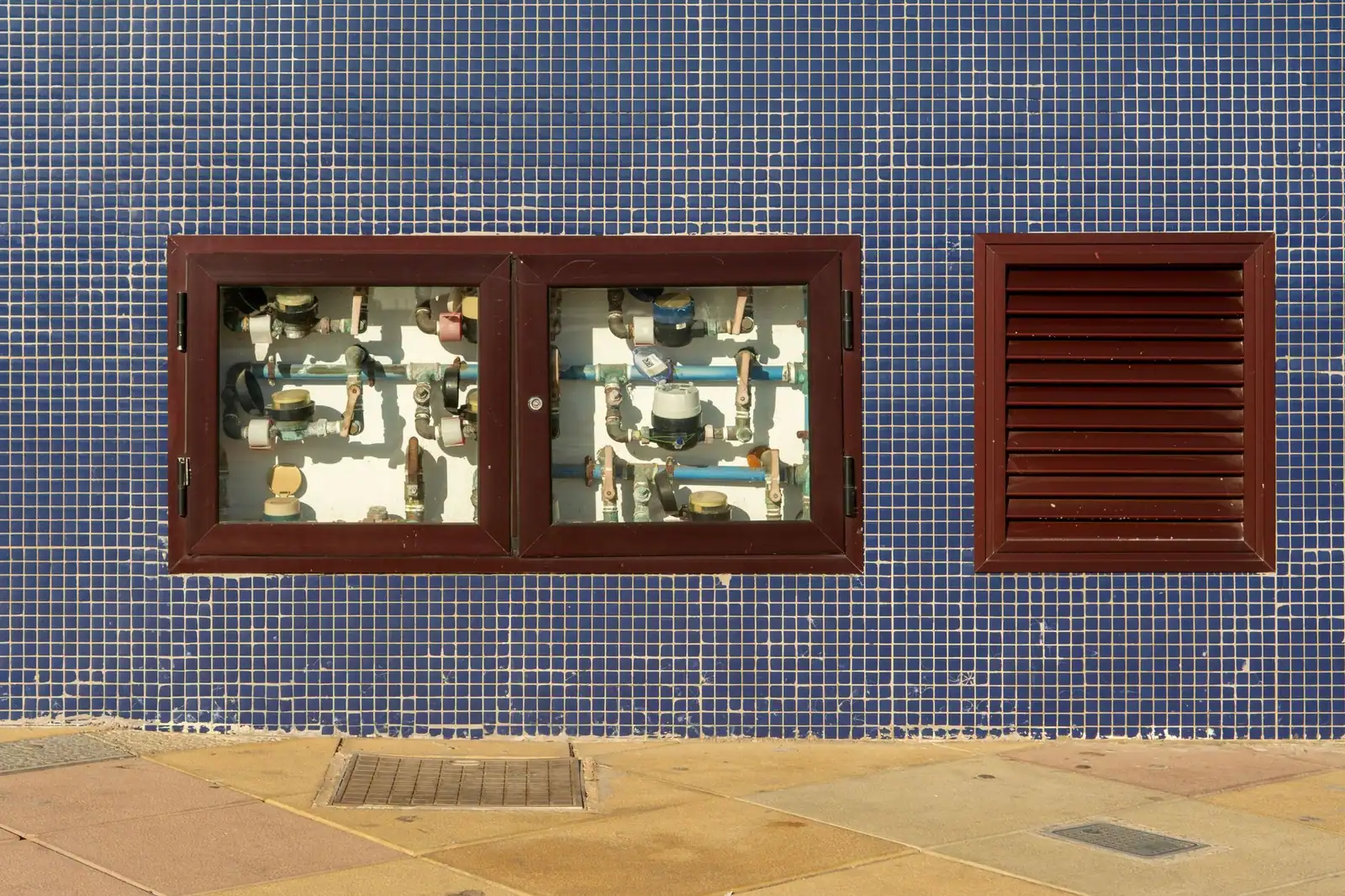 Exposed water meters and their pipework set into a tiled wall