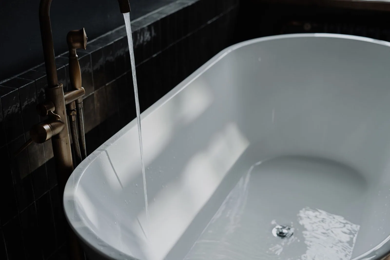 Water running into a modern bathtub in a bright bathroom