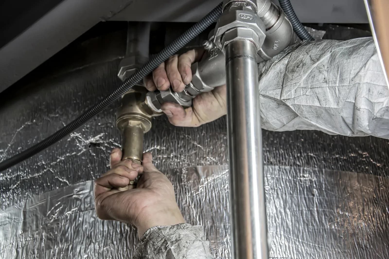 A plumber fitting steel pipe on a main line, the work a whole-house install means