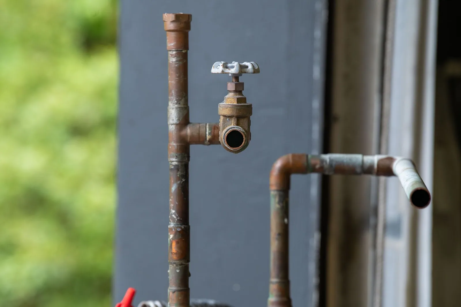 An old water pipe and its shut-off valve, rusted and corroded after years in service