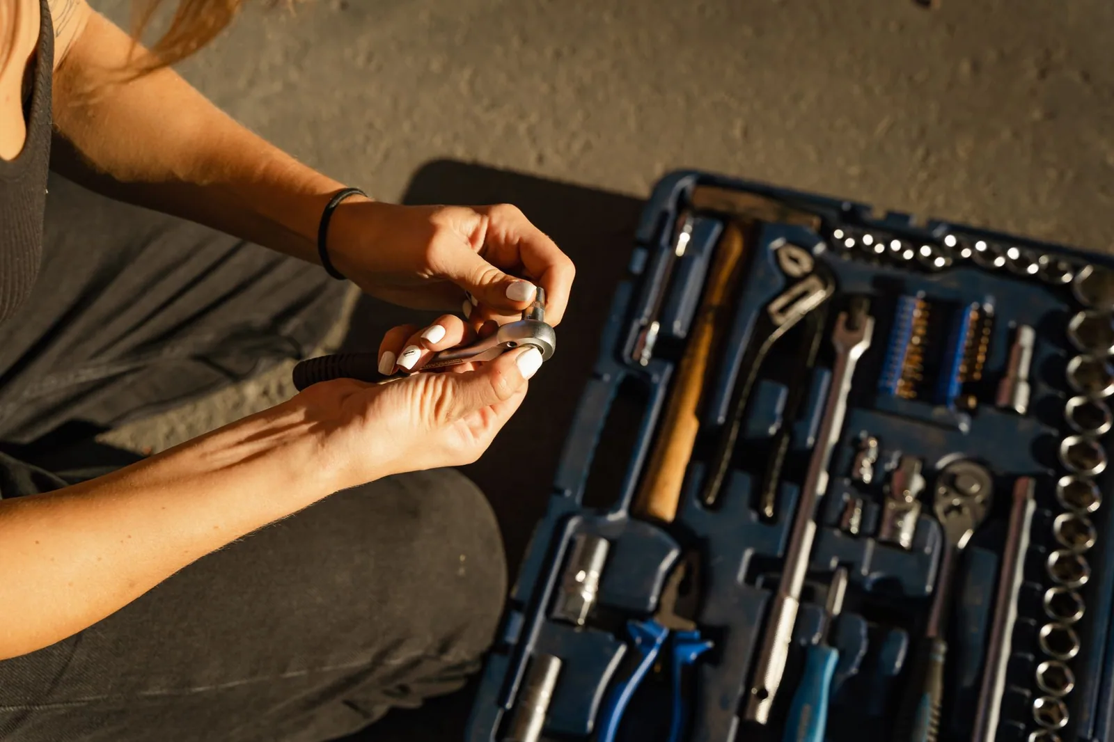 Hands lifting a tool out of an open toolset on a workbench