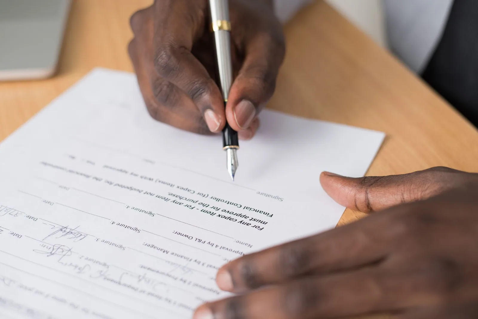 A hand signing a printed agreement with a fountain pen