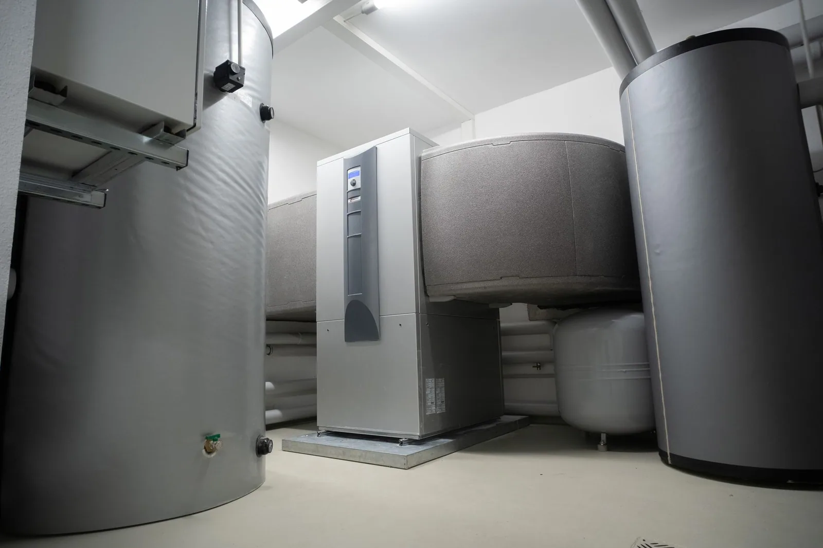Insulated hot water storage tanks around a heat pump in a basement mechanical room