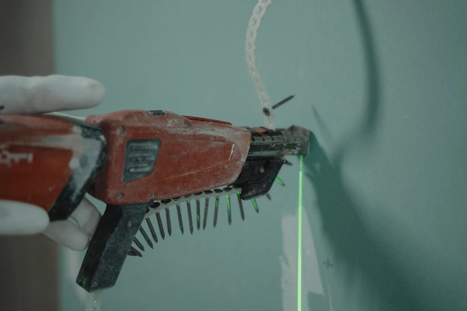 A collated screw gun driving fixings into a wall during an installation