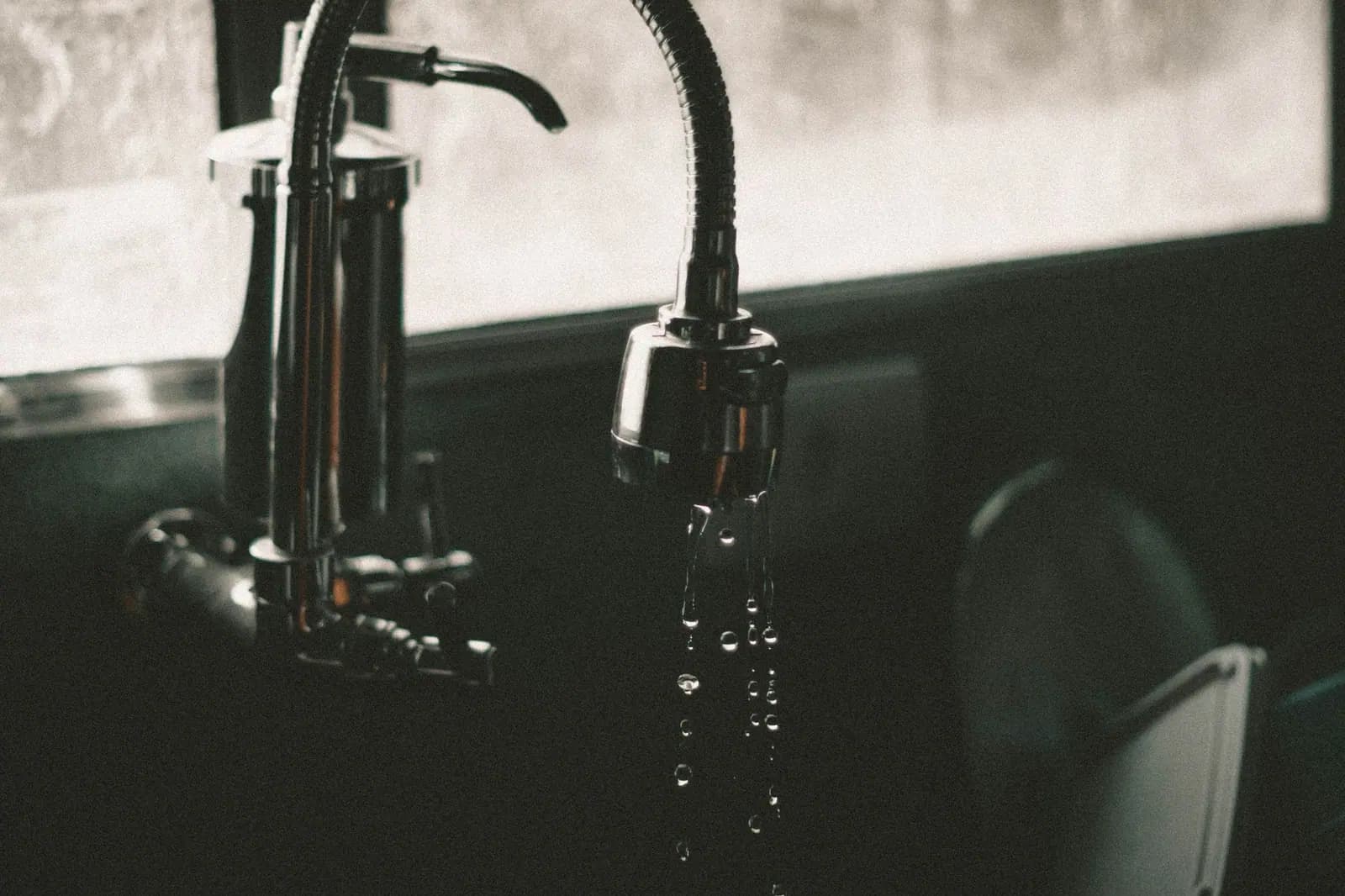 A kitchen tap running thin into the sink, the single outlet an under-sink reverse osmosis system feeds