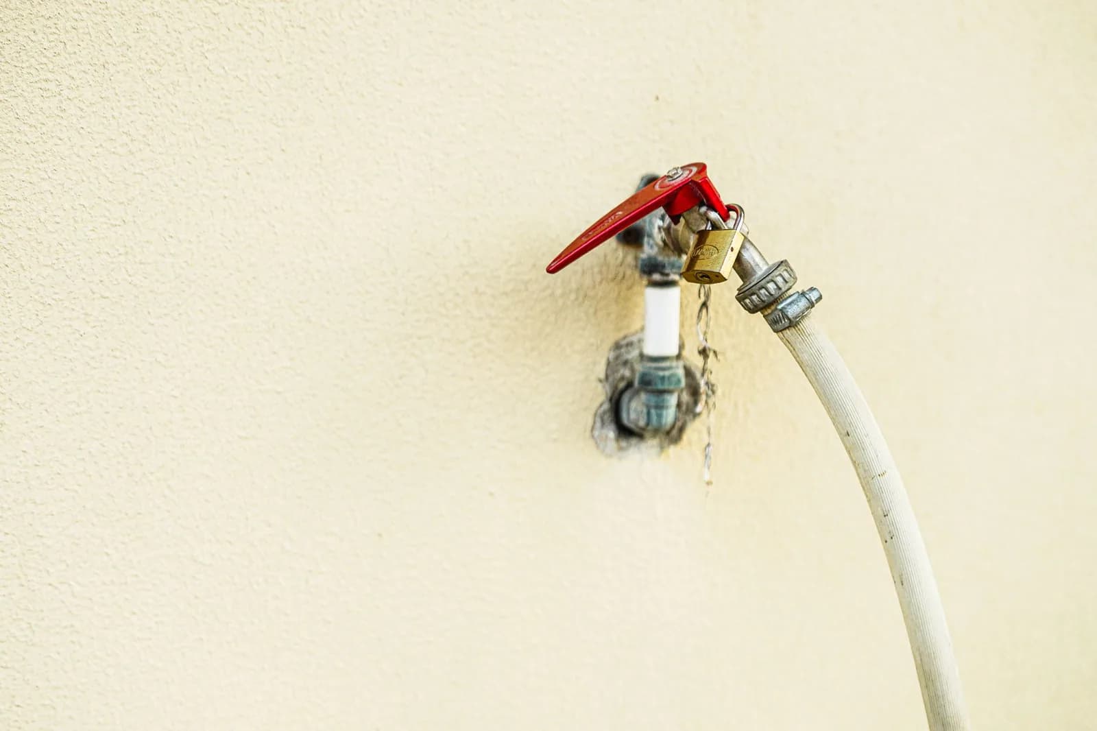 An outdoor water spigot with a red handle, the fitting a campground hose screws onto