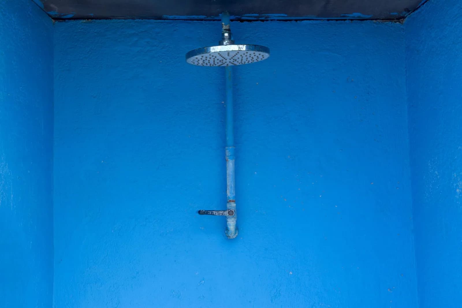 A metal rain shower head on a blue textured shower wall