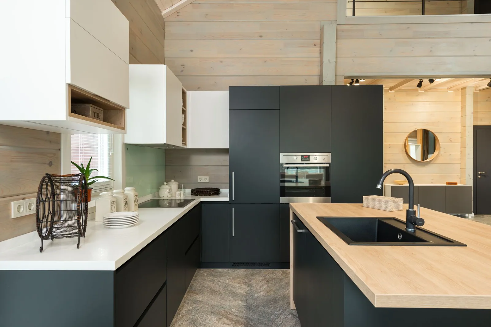 A minimalist kitchen with black and white cabinets and a sink set into the counter