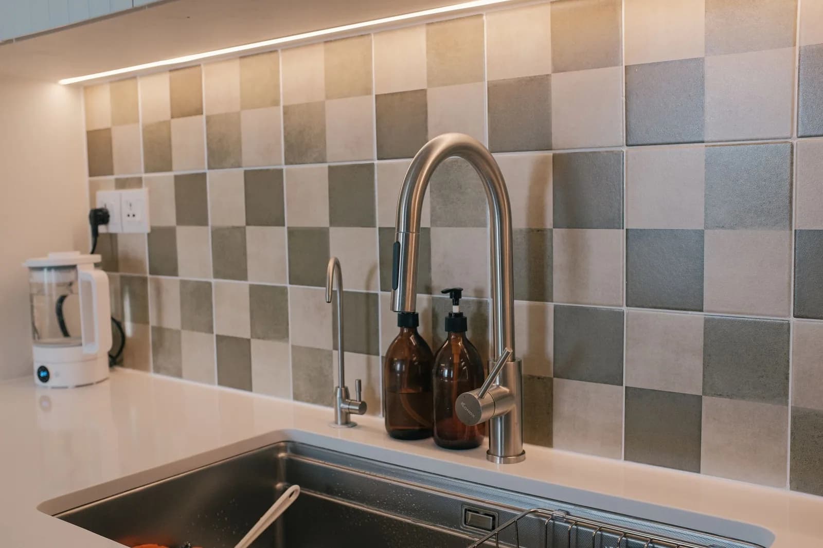 A sleek kitchen faucet against a tiled backsplash