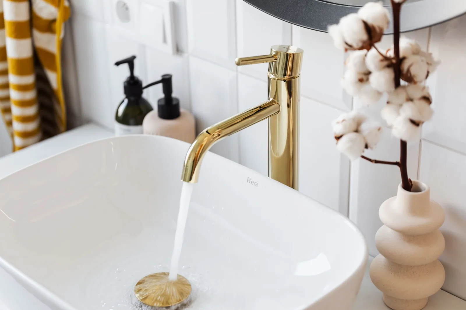 Water running from a gold bathroom faucet into a white basin