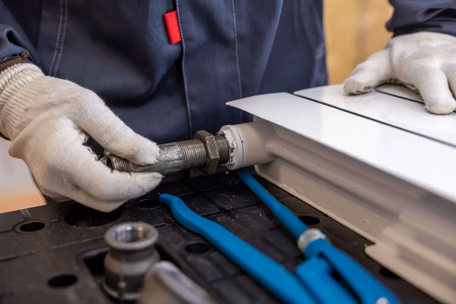 A plumber fitting a pipe with a wrench during an indoor installation