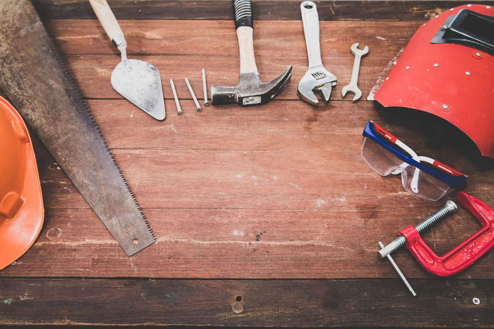 Hand tools laid out flat on a wooden workbench before a job