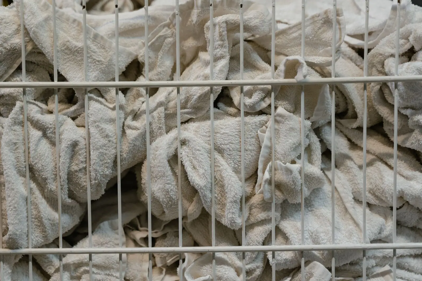 Greying, worn towels piled in a laundry basket after washing