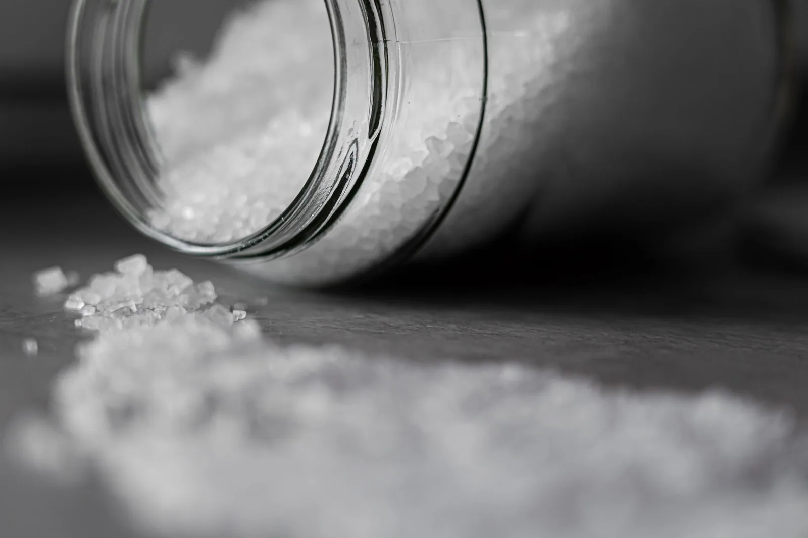Coarse salt pouring from a tipped glass jar