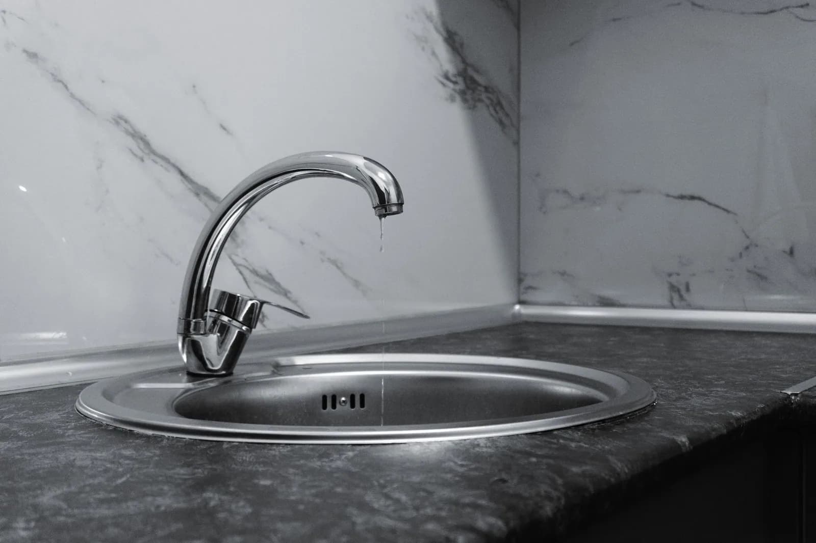 A chrome faucet over a clean stainless kitchen sink