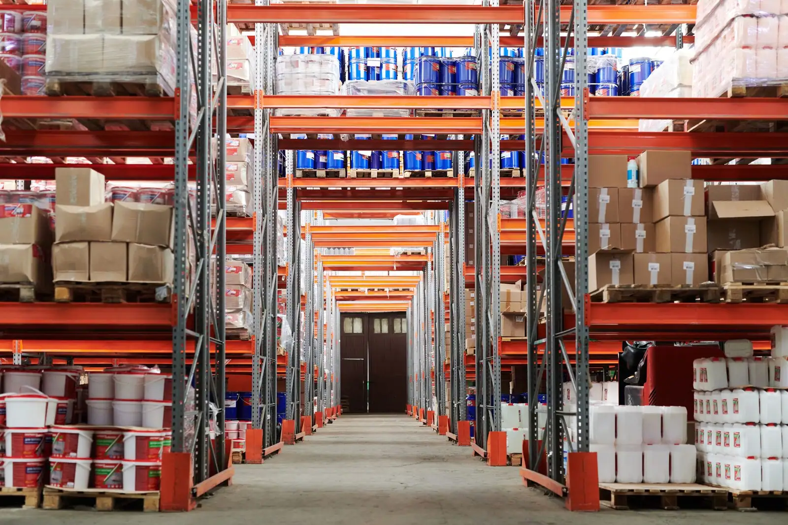 Warehouse racking stacked with pallets of boxed goods down a long aisle