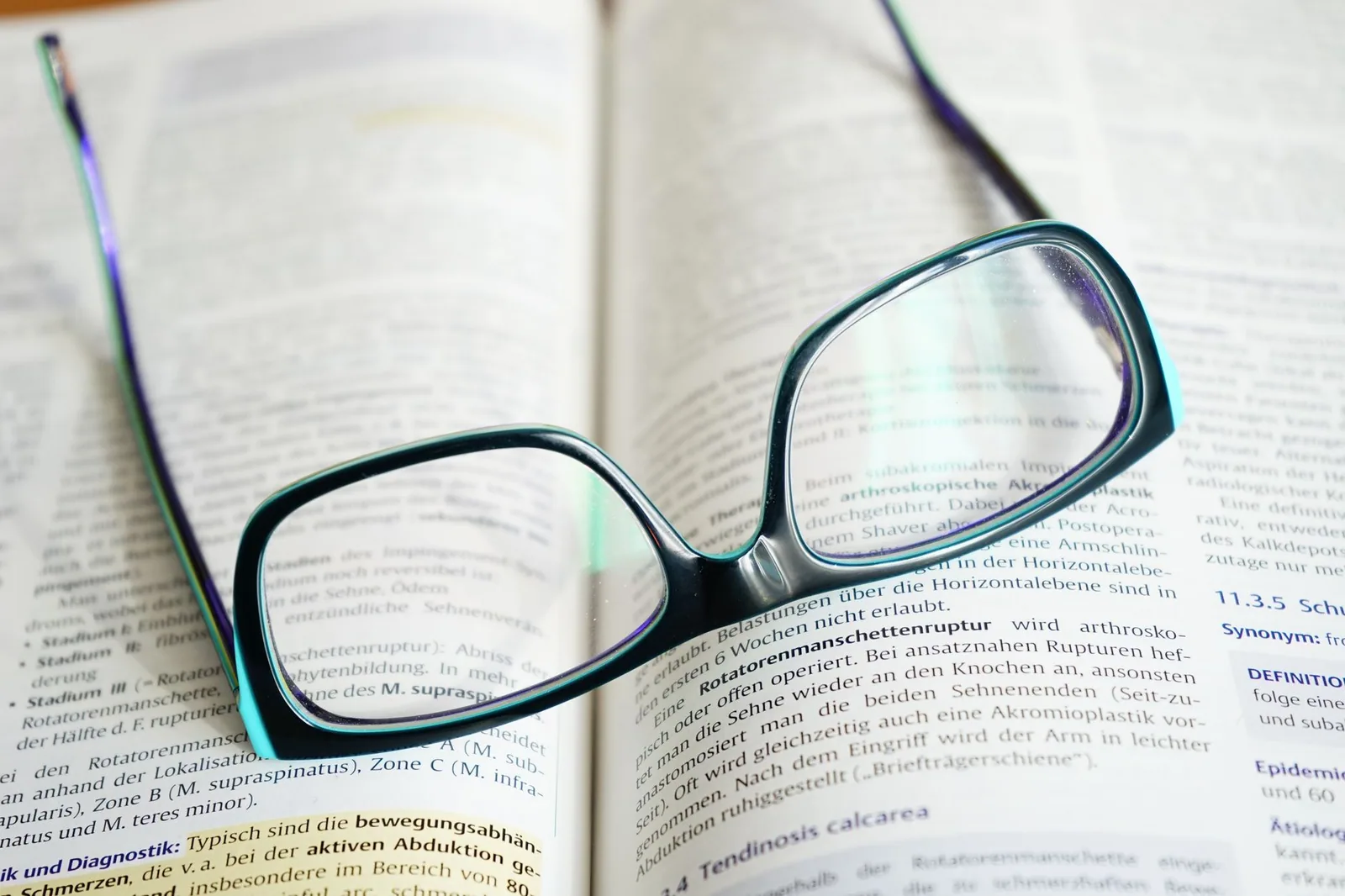 Reading glasses resting on an open book of dense small print