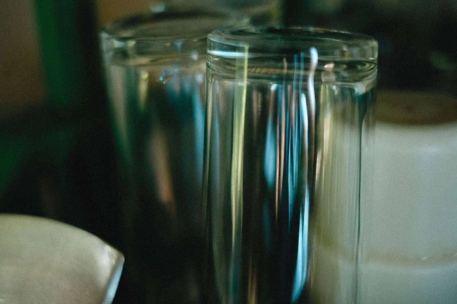 Two drinking glasses standing side by side, catching the light against a dark background