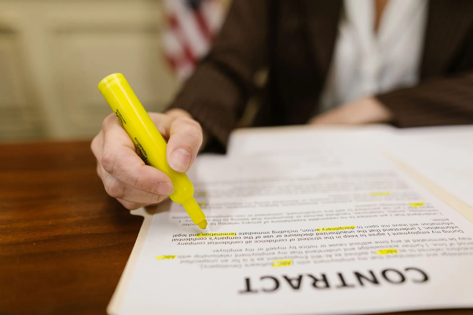 A hand running a highlighter across a clause in a printed contract